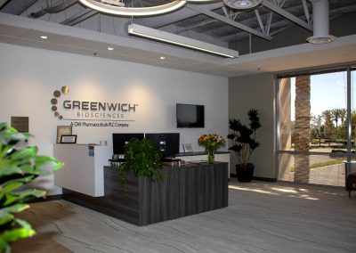 Office reception area of Greenwich Biosciences with a desk, plants, and company logo on the wall.