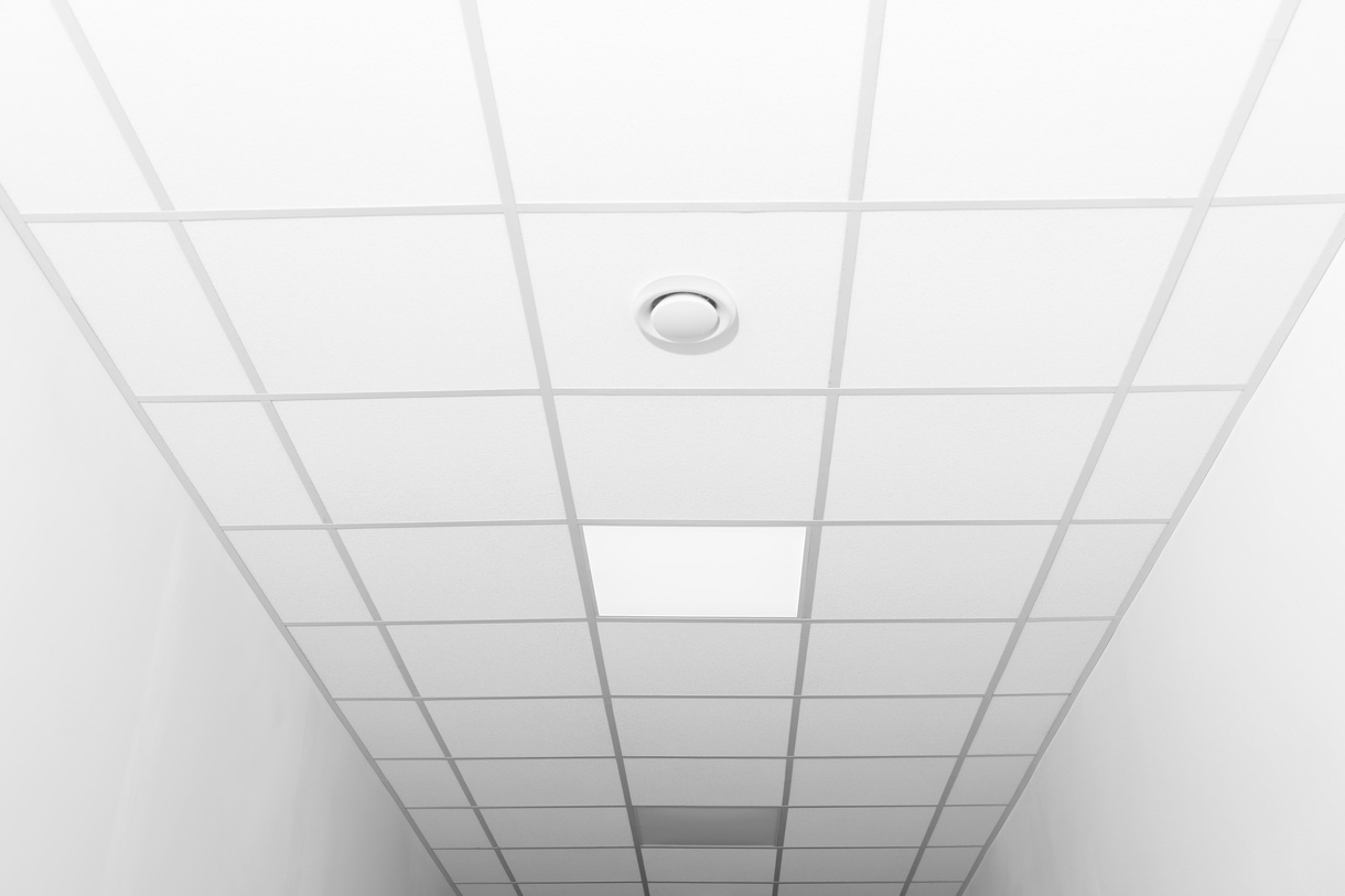 Acoustic Ceiling Installation White acoustic ceiling tiles with a central circular vent and rectangular lighting panels.