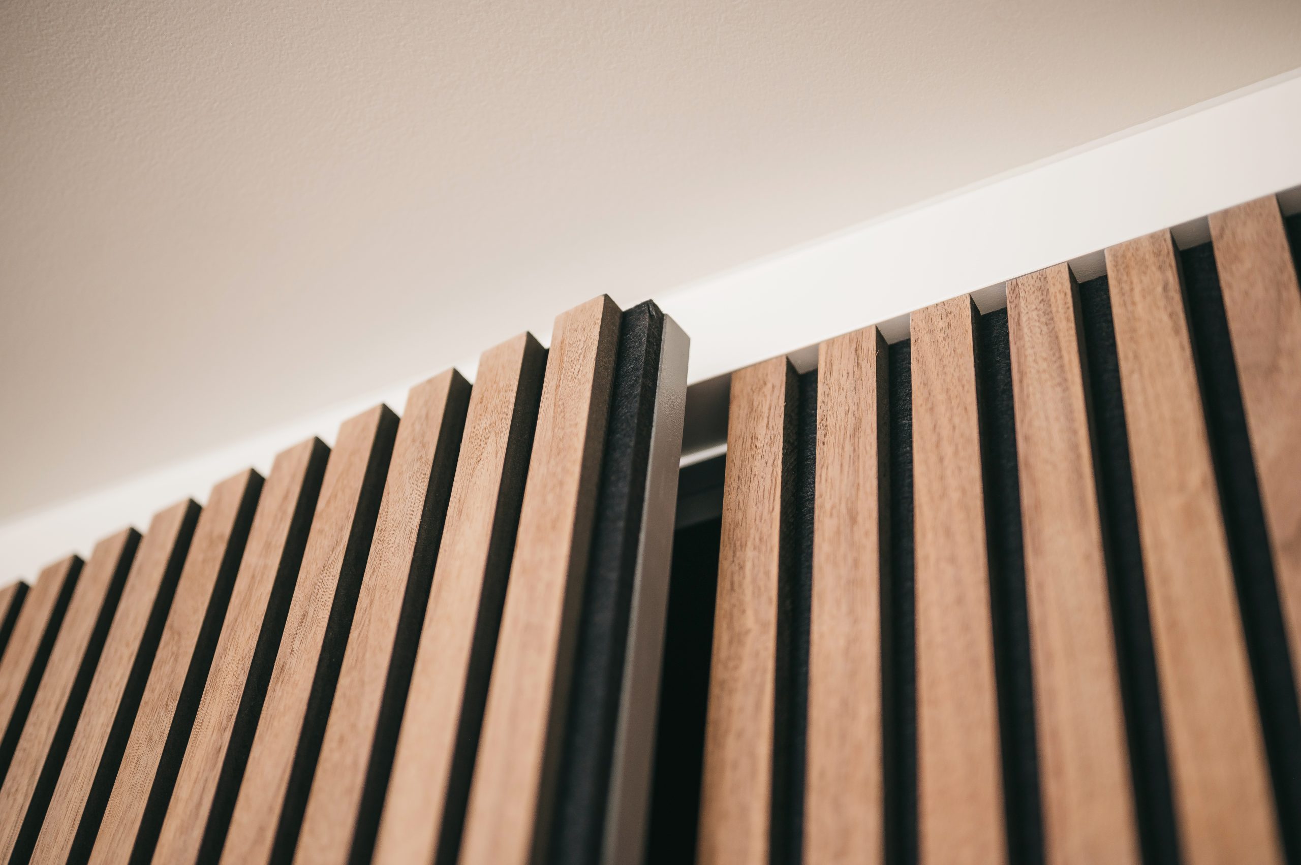 acoustic wall panels Close-up of wooden slats with black gaps, part of a ceiling design.